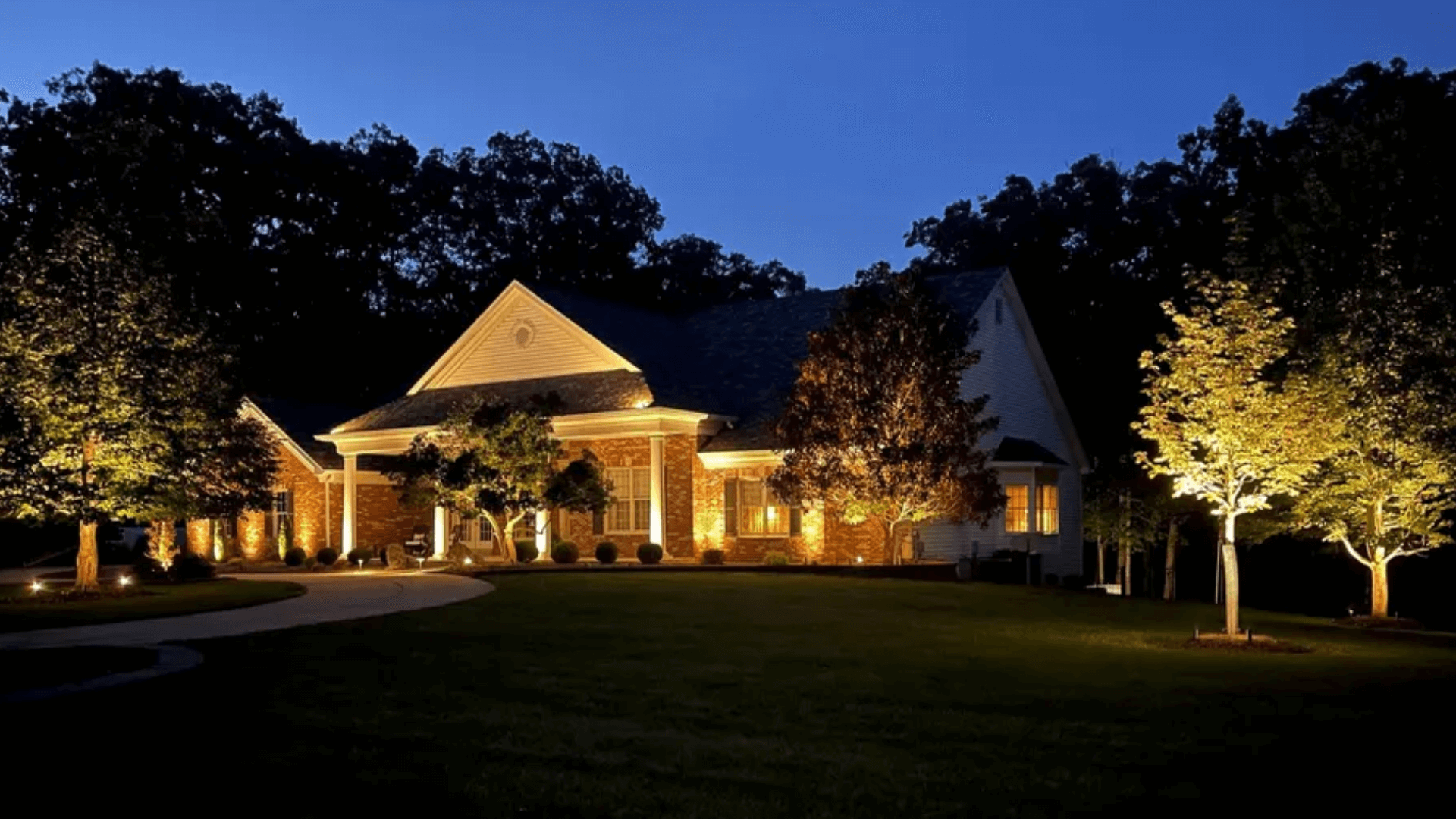 Twilight landscape lighting design with tree uplights facade washing and path lights at luxury home by NxGen Outdoors