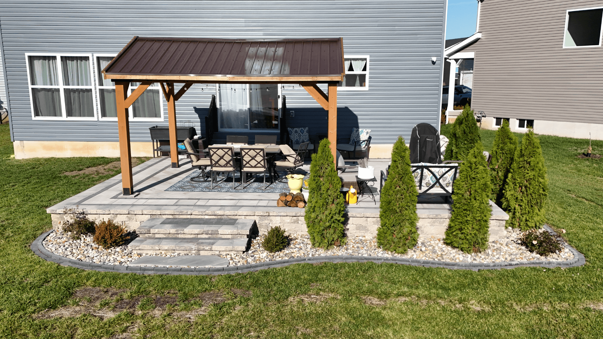 Completed paver patio with stone retaining wall steps and landscaping by NxGen Outdoors