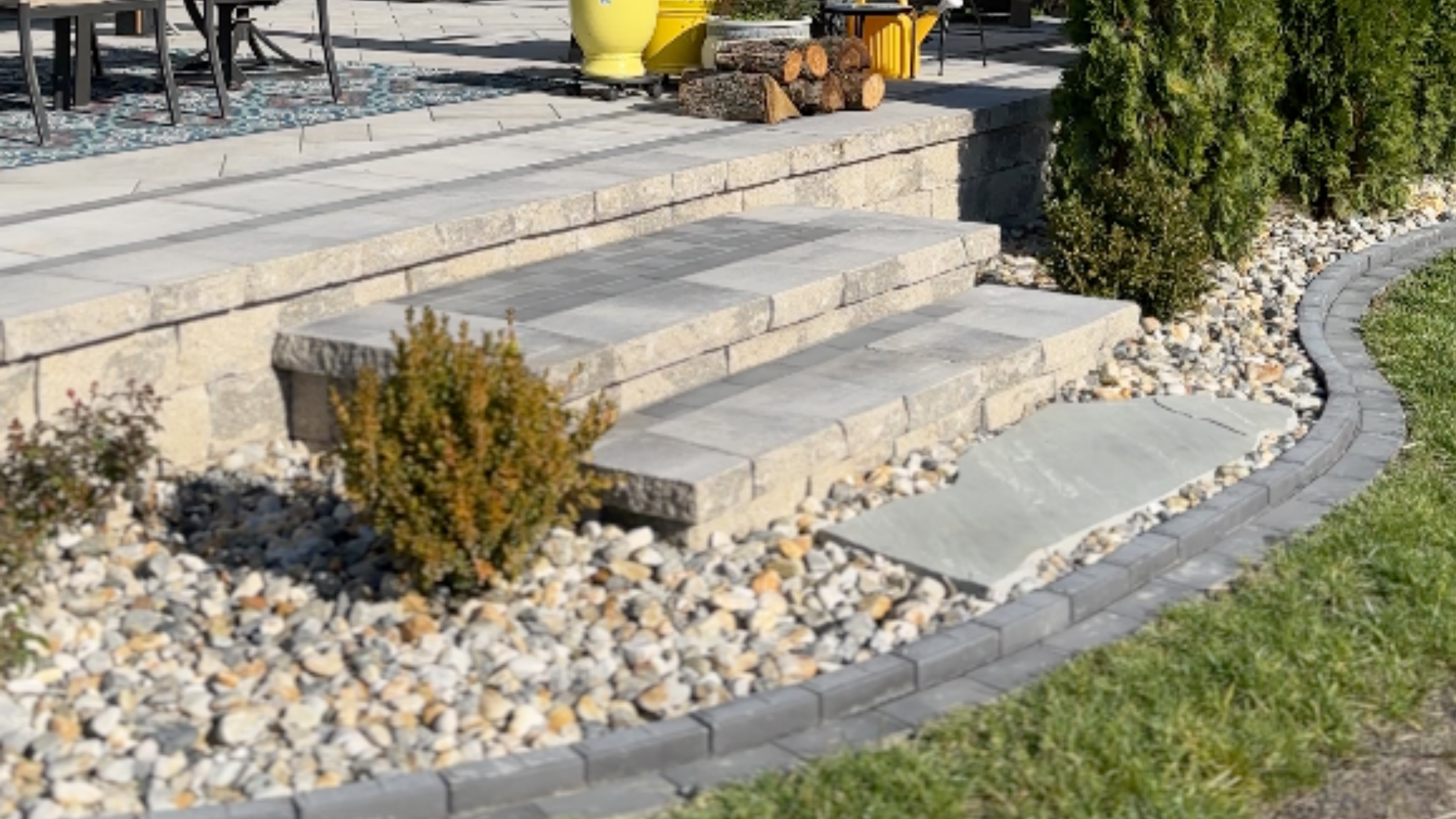 Natural flagstone steps with river rock borders and stone retaining wall by NxGen Outdoors