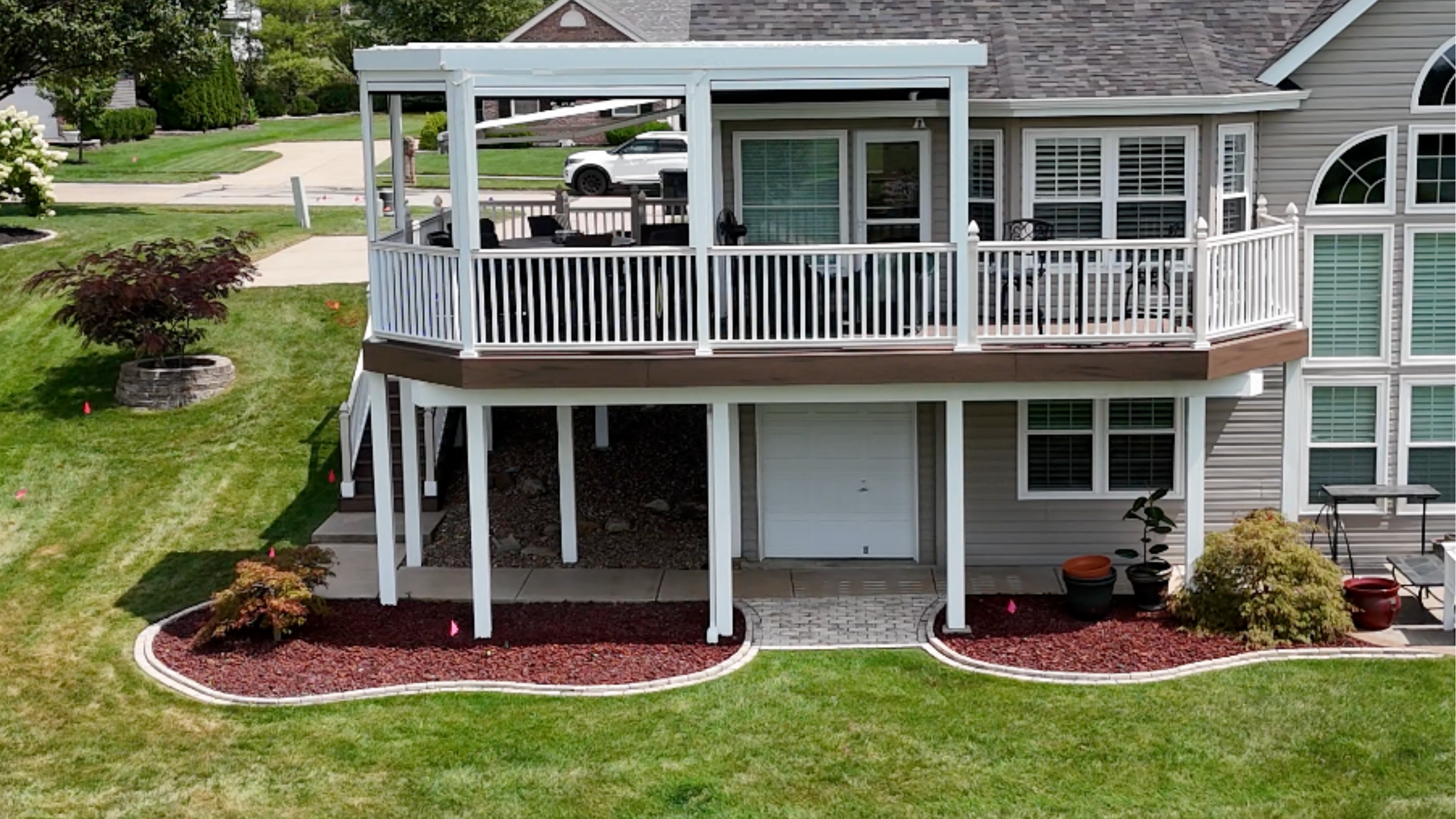 Two-level composite deck with white railings brick fireplace and paver patio